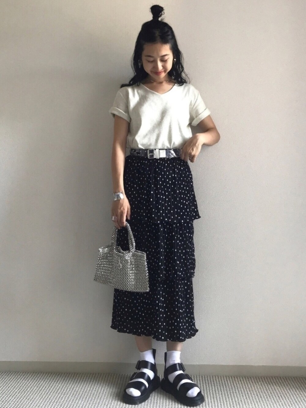 ブラック系のスカート、ベージュ系のTシャツ/カットソー、ブラック系のサンダルを着用したレディースの春コーディネートの1枚目の写真