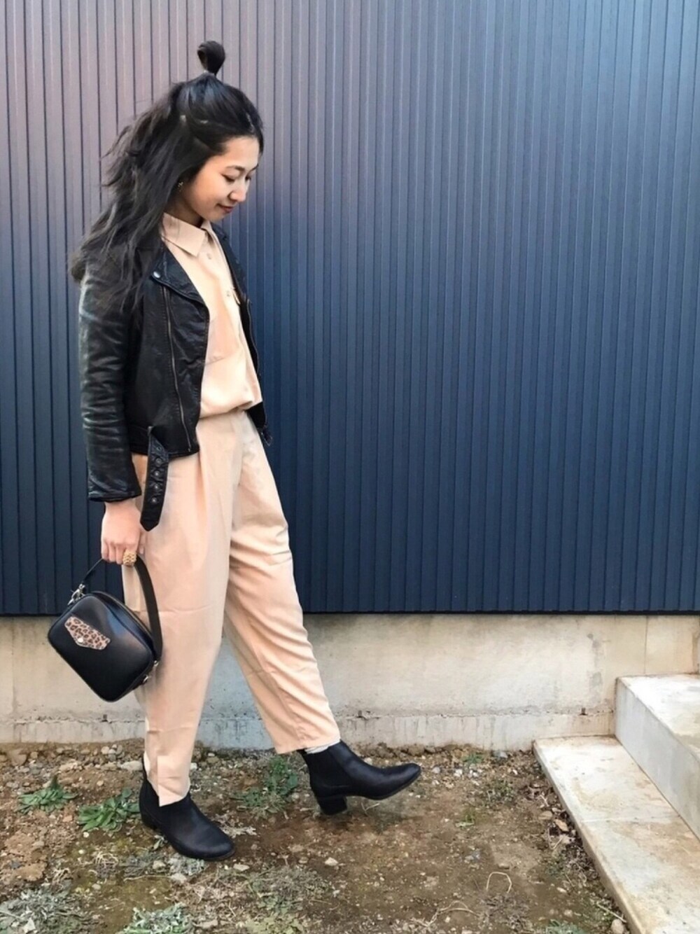 ブラック系のライダースジャケット、ベージュ系のワンピース、ブラック系のショルダーバッグを着用したレディースの冬コーディネートの1枚目の写真