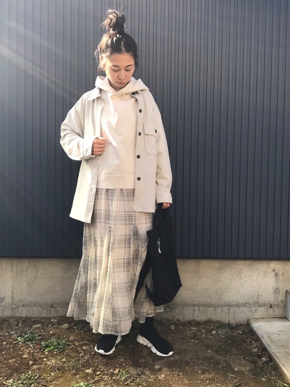グレー系のカバーオール、ホワイト系のパーカー、ベージュ系のスカートを着用したレディースの冬コーディネートの1枚目の写真
