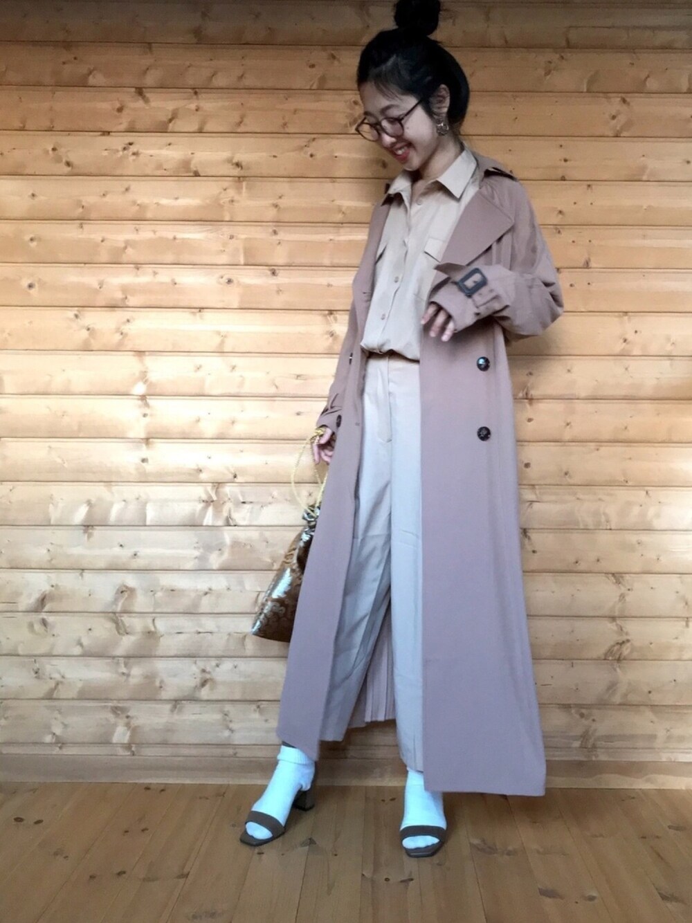 ベージュ系のワンピース、ブラウン系のハンドバッグ、ベージュ系のトレンチコートを着用したレディースの春コーディネートの1枚目の写真