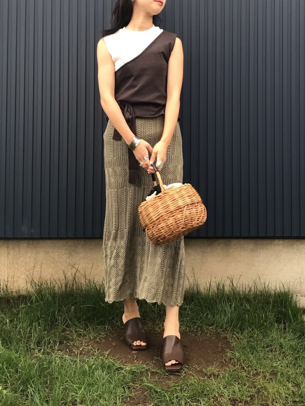 グリーン系のスカート、ホワイト系のTシャツ/カットソー、ブラウン系のニット/セーターを着用したレディースの夏コーディネートの1枚目の写真