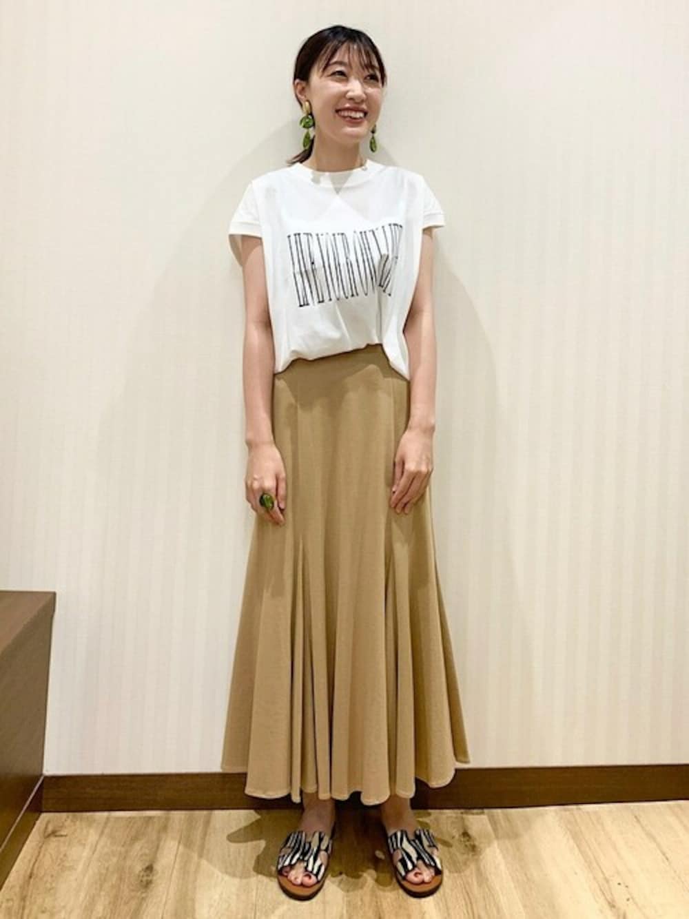 ホワイト系のTシャツ/カットソー、イエロー系のスカート、グリーン系のサンダルを着用したレディースの夏コーディネートの1枚目の写真