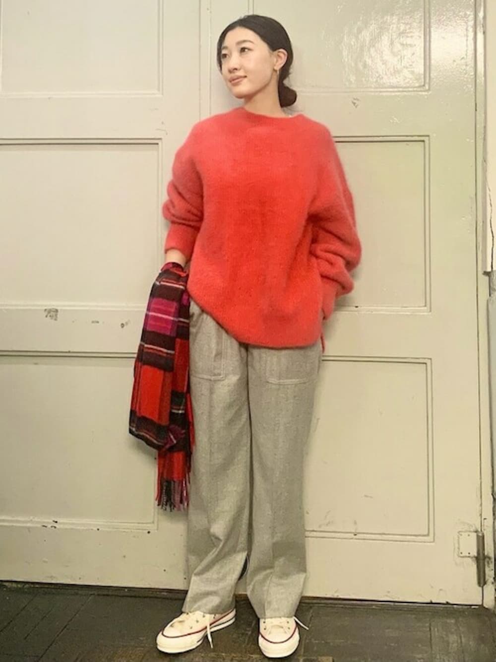 グレー系のその他パンツ、ベージュ系のスニーカー、レッド系のニット/セーターを着用したレディースの冬コーディネートの1枚目の写真