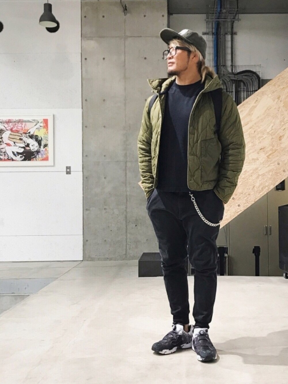 ブラック系のTシャツ/カットソー、グリーン系のミリタリージャケット、ブラック系のパンツを着用したメンズの冬コーディネートの1枚目の写真