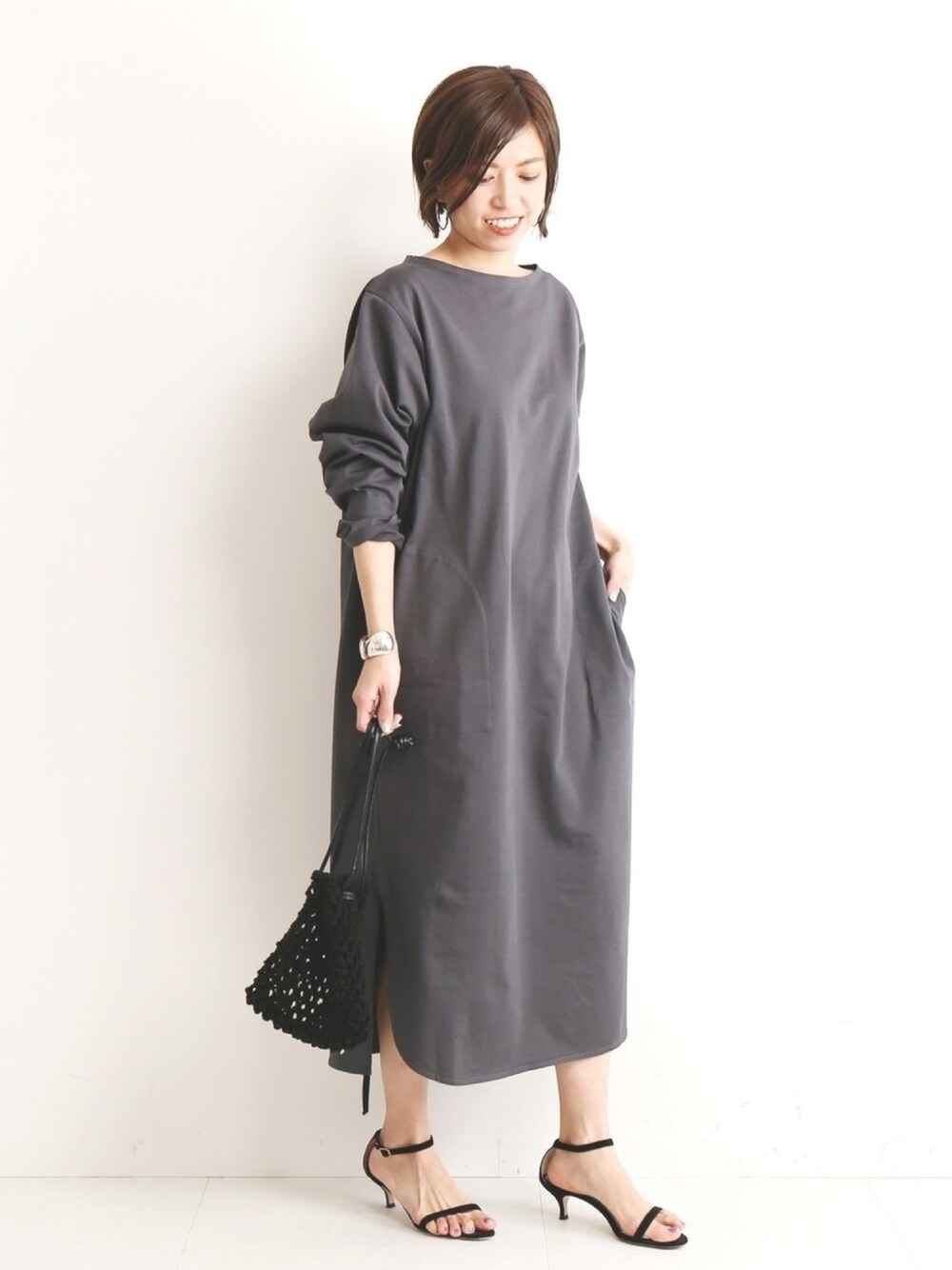 グレー系のワンピース、ブラック系のハンドバッグ、ブラック系のサンダルを着用したレディースの春コーディネートの1枚目の写真