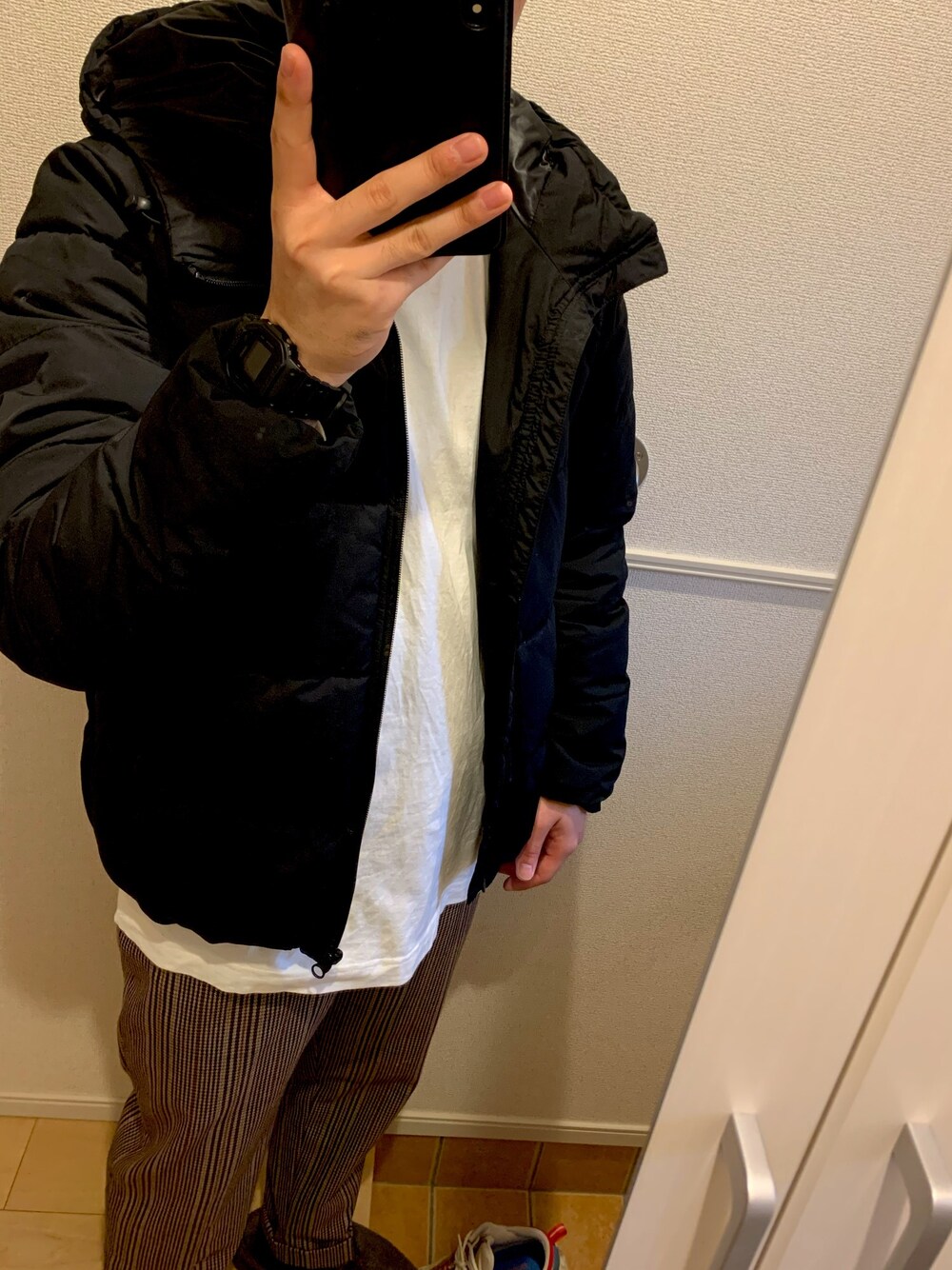 ホワイト系のTシャツ/カットソー、ブラック系のダウンジャケット/コート、その他のスラックスを着用したメンズの冬コーディネートの1枚目の写真