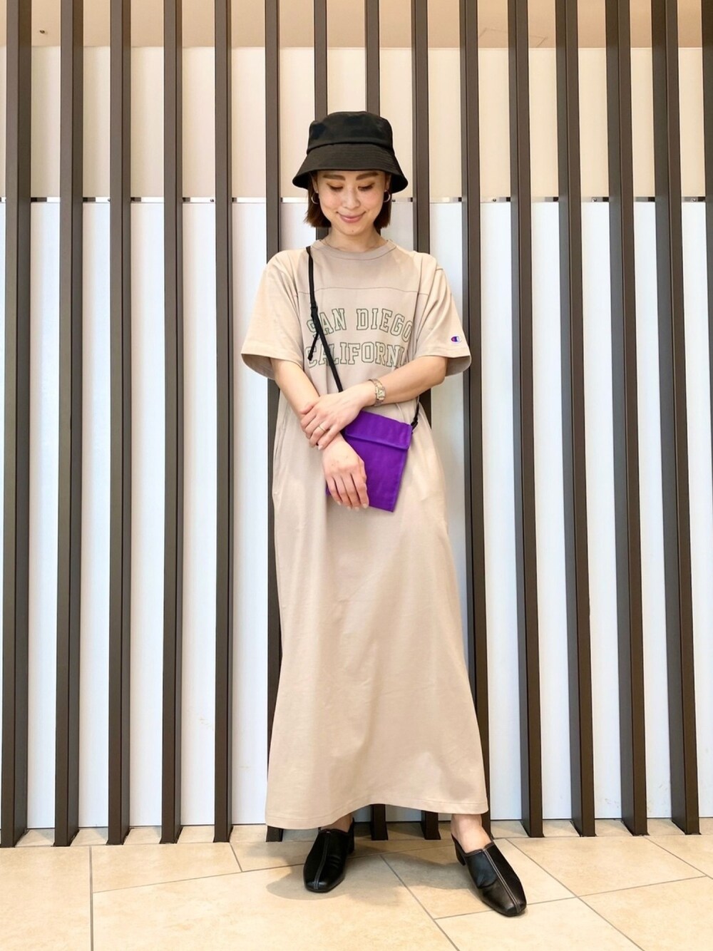 ベージュ系のワンピース、パープル系のショルダーバッグ、ブラック系のサンダルを着用したレディースの春コーディネートの1枚目の写真