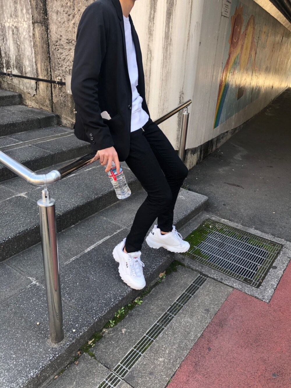 ブラック系のテーラードジャケット、ブラック系のデニムパンツ、ホワイト系のスニーカーを着用したメンズの冬コーディネートの1枚目の写真