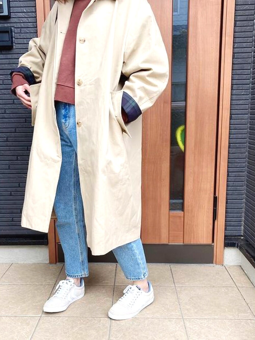ベージュ系のトレンチコート、ベージュ系のスニーカー、ブルー系のデニムパンツを着用したレディースの春コーディネートの1枚目の写真