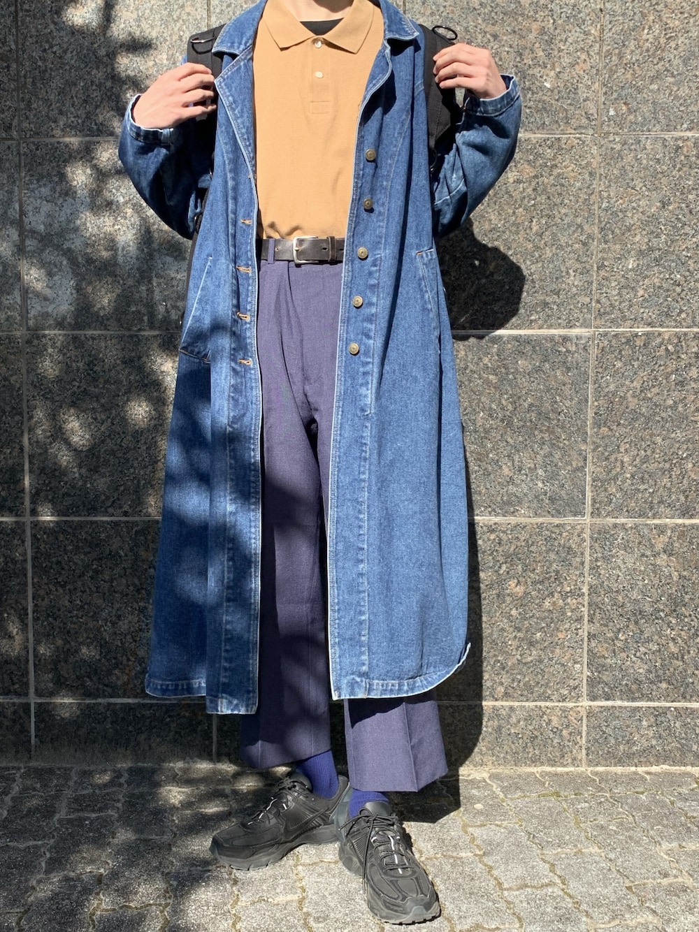 ブルー系のチェスターコート、ベージュ系のポロシャツ、ブラック系のTシャツ/カットソーを着用したメンズの冬コーディネートの1枚目の写真