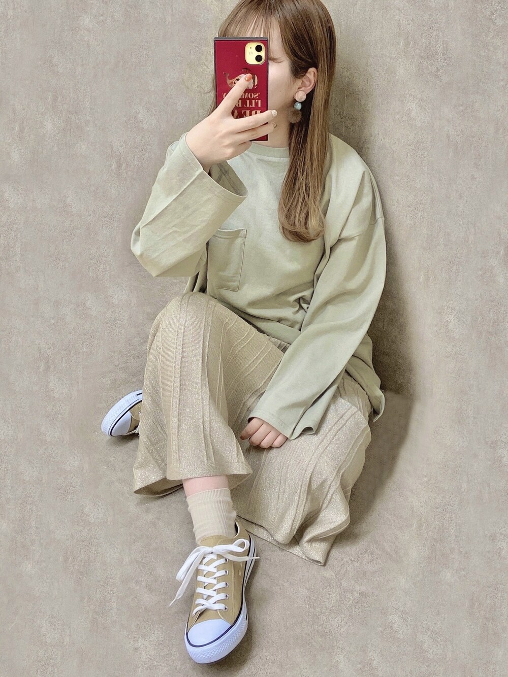 グリーン系のTシャツ/カットソー、ベージュ系のスカート、ベージュ系のスニーカーを着用したレディースの冬コーディネートの1枚目の写真