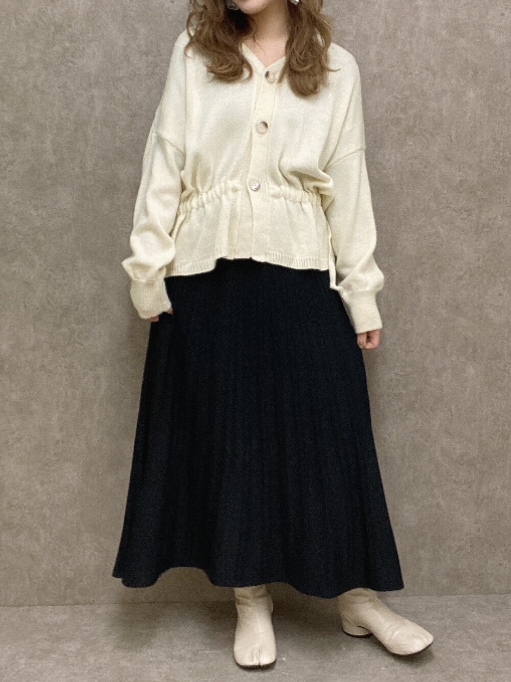 ホワイト系のカーディガン/ボレロ、ブルー系のスカート、ホワイト系のブーツを着用したレディースの冬コーディネートの1枚目の写真