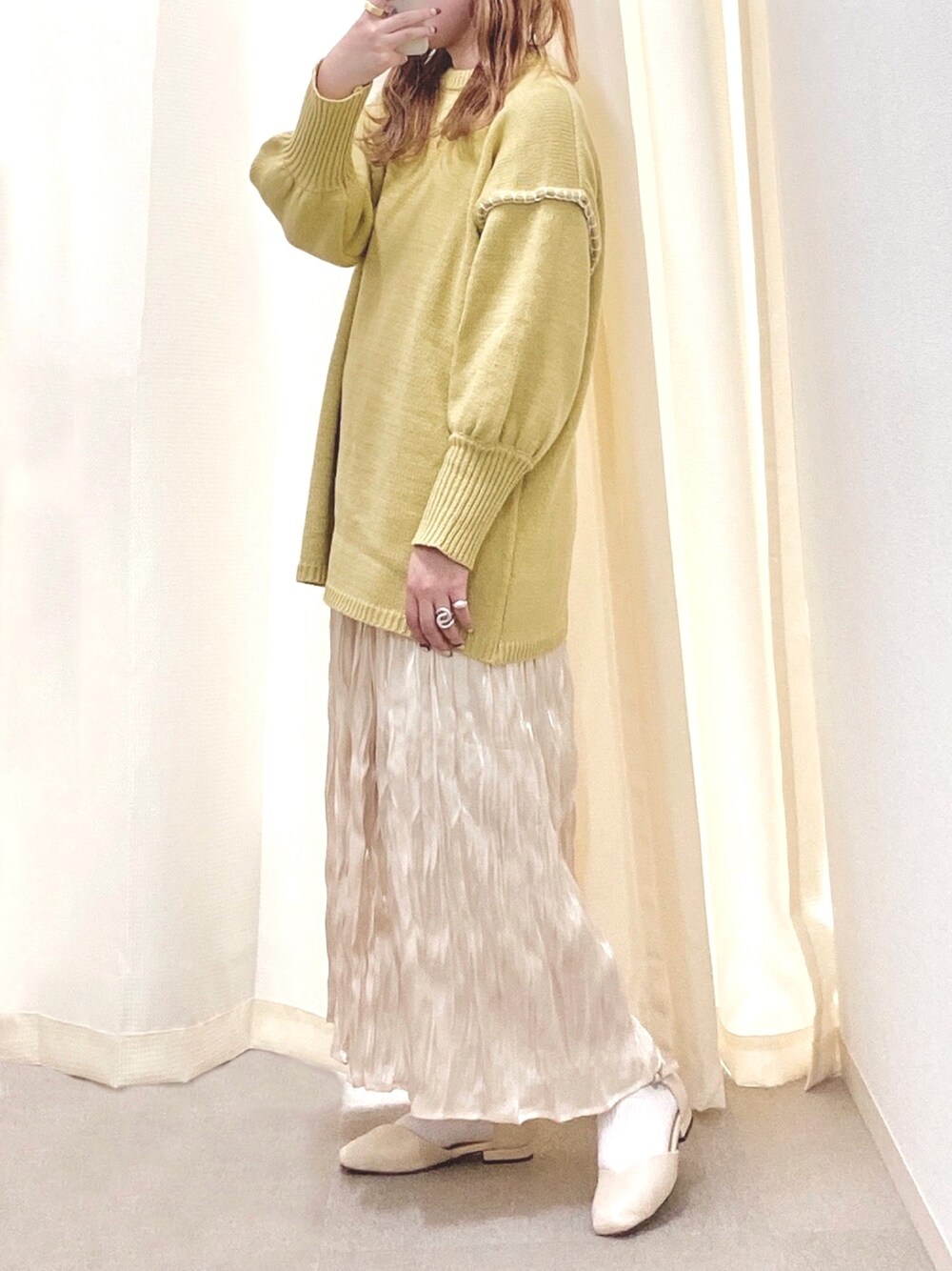 イエロー系のニット/セーター、ホワイト系のスカート、ベージュ系のパンプスを着用したレディースの春コーディネートの1枚目の写真