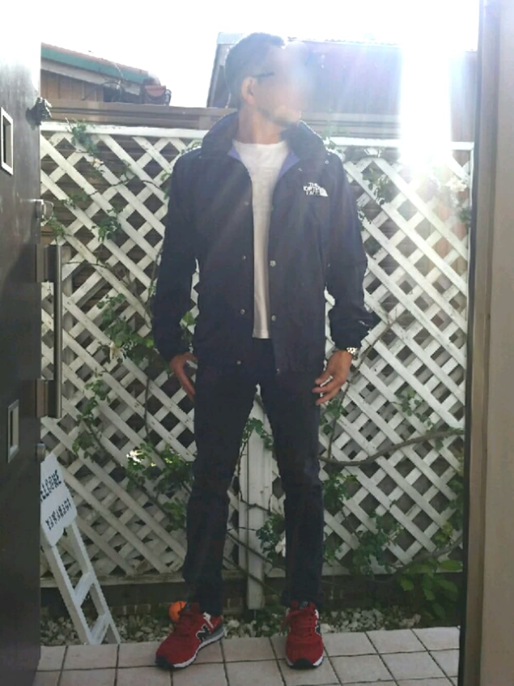 レッド系のスニーカー、ブラック系のデニムパンツ、ブラック系のマウンテンパーカーを着用したメンズの春コーディネートの1枚目の写真