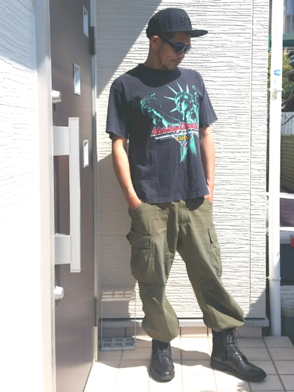 ブラック系のブーツ、グリーン系のカーゴパンツ、ブラック系のTシャツ/カットソーを着用したメンズの春コーディネートの1枚目の写真