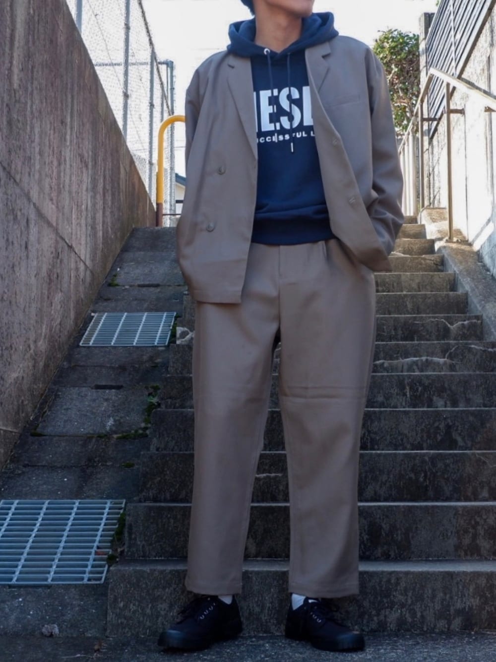 ブラック系のスニーカー、ベージュ系のセットアップ、ブルー系のパーカーを着用したメンズの冬コーディネートの1枚目の写真