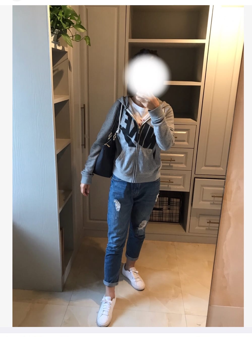 グレー系のスタジャン、ブラック系のショルダーバッグ、ホワイト系のスニーカーを着用したレディースの秋コーディネートの1枚目の写真