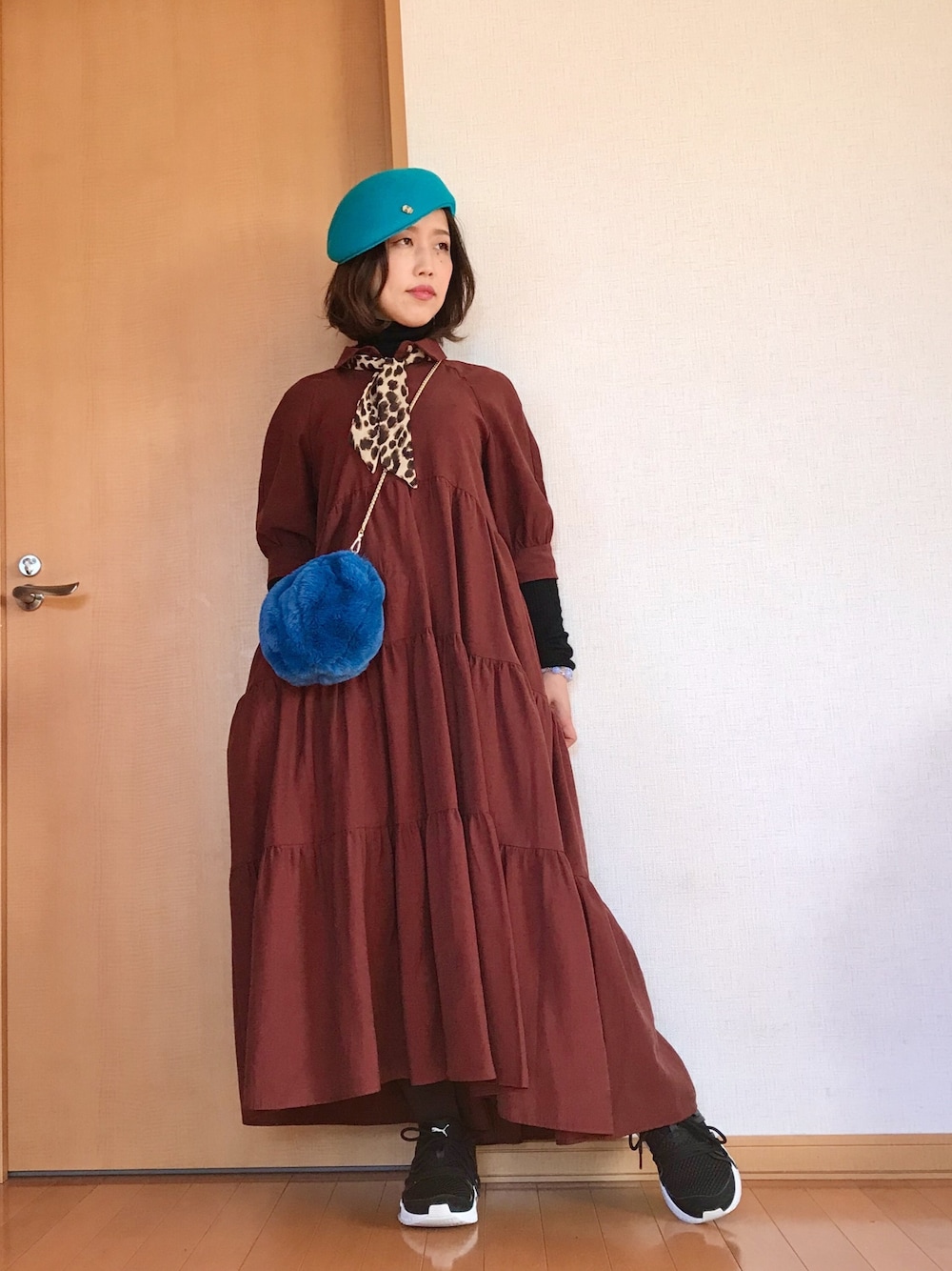 ブラウン系のワンピース、ブルー系のショルダーバッグ、ベージュ系のストール/ショールを着用したレディースの冬コーディネートの1枚目の写真