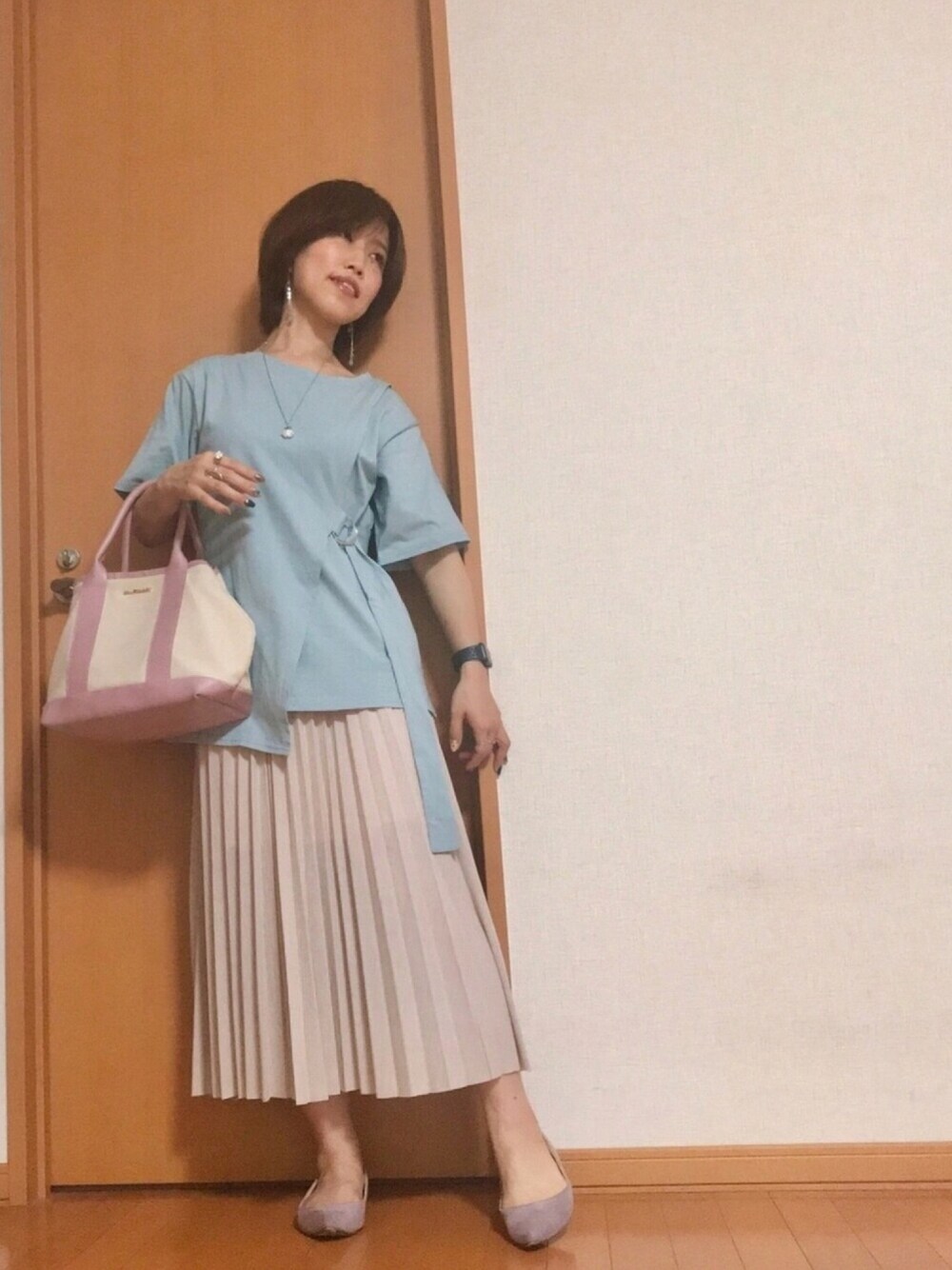 ピンク系のトートバッグ、ベージュ系のスカート、ブルー系のTシャツ/カットソーを着用したレディースの夏コーディネートの1枚目の写真