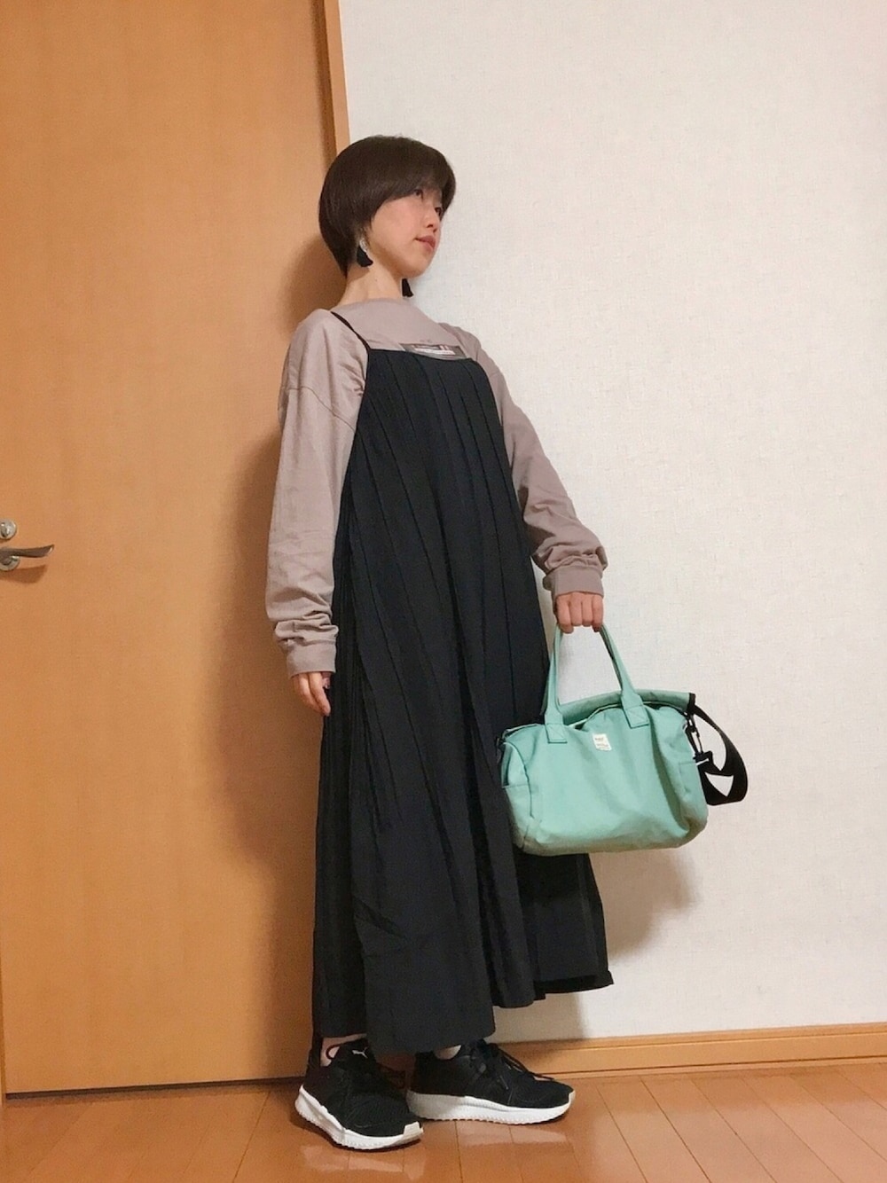 ブラック系のワンピース、ベージュ系のTシャツ/カットソー、ブラック系のスニーカーを着用したレディースの秋コーディネートの1枚目の写真