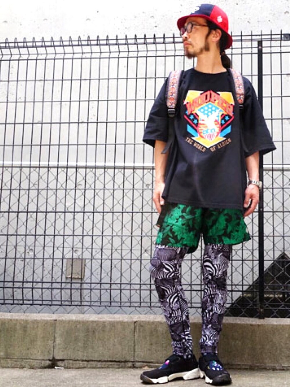 グリーン系のその他パンツ、ブラック系のTシャツ/カットソー、レッド系のハットを着用したメンズの春コーディネートの1枚目の写真