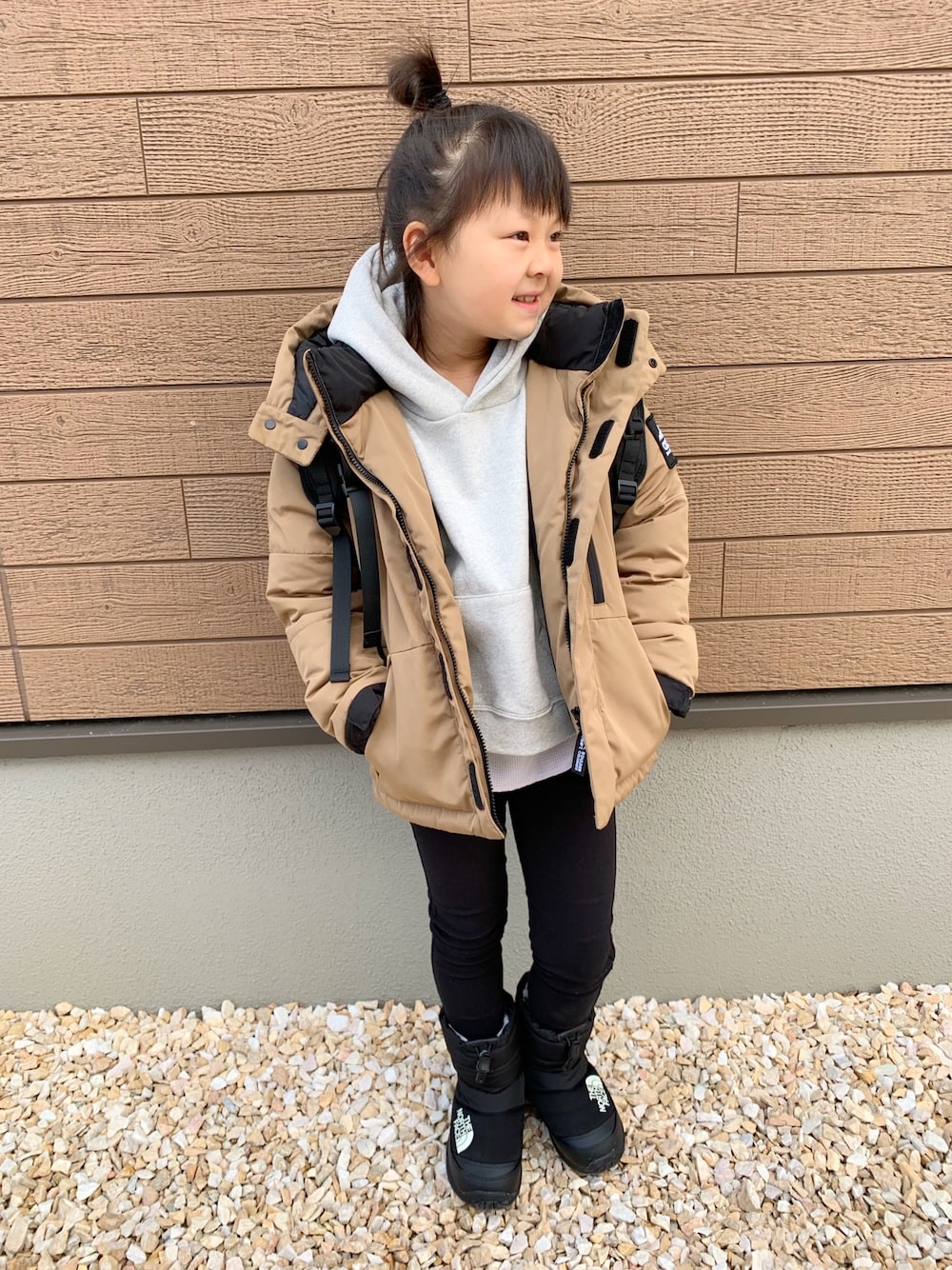 ベージュ系のダウンジャケット/コート、グレー系のパーカー、ブラック系のその他パンツを着用したキッズの冬コーディネートの1枚目の写真