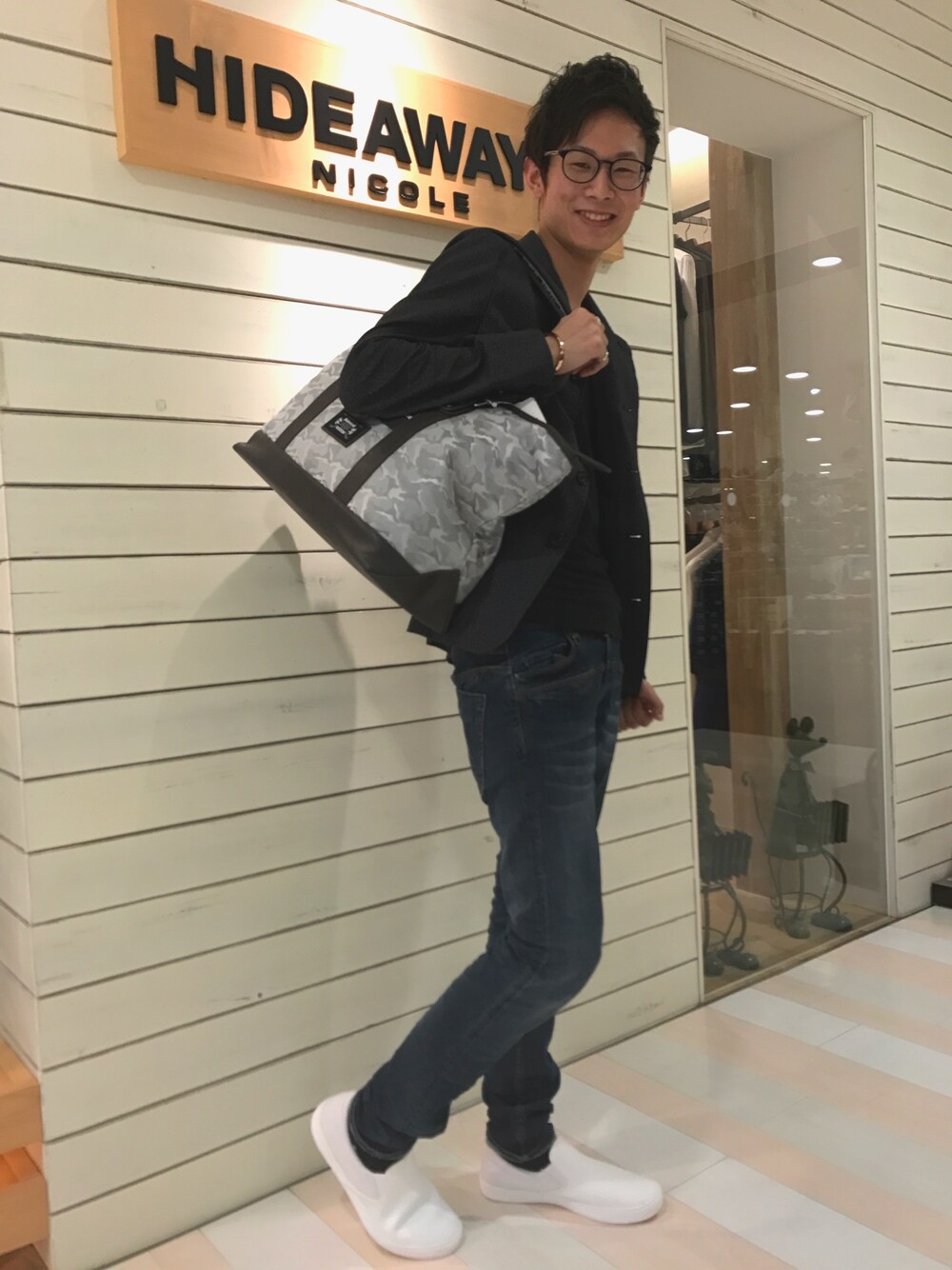 グレー系のトートバッグ、ブラック系のテーラードジャケット、ブルー系のデニムパンツを着用したメンズの春コーディネートの1枚目の写真