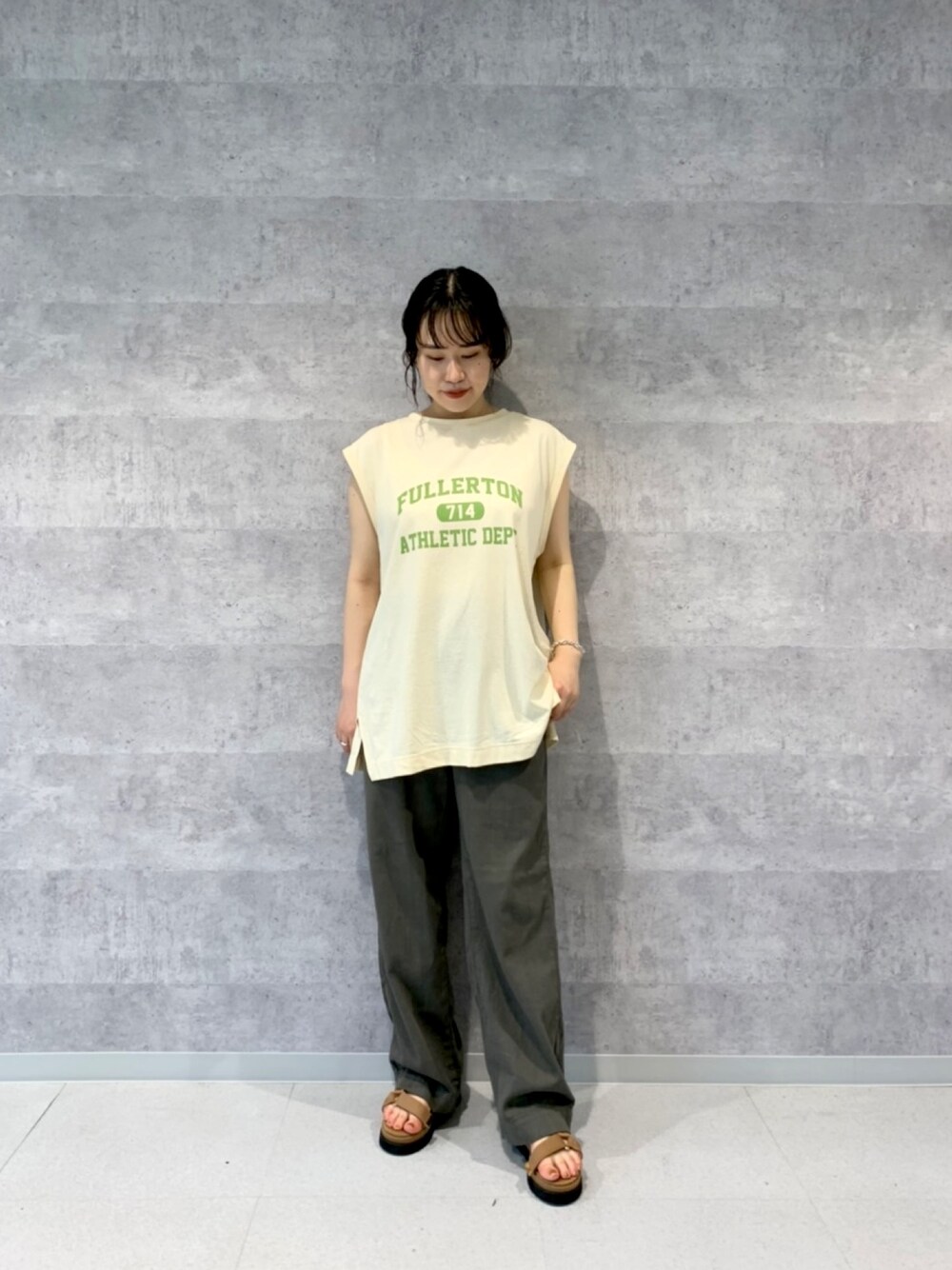 ベージュ系のTシャツ/カットソー、グリーン系のデニムパンツ、イエロー系のサンダルを着用したレディースの春コーディネートの1枚目の写真