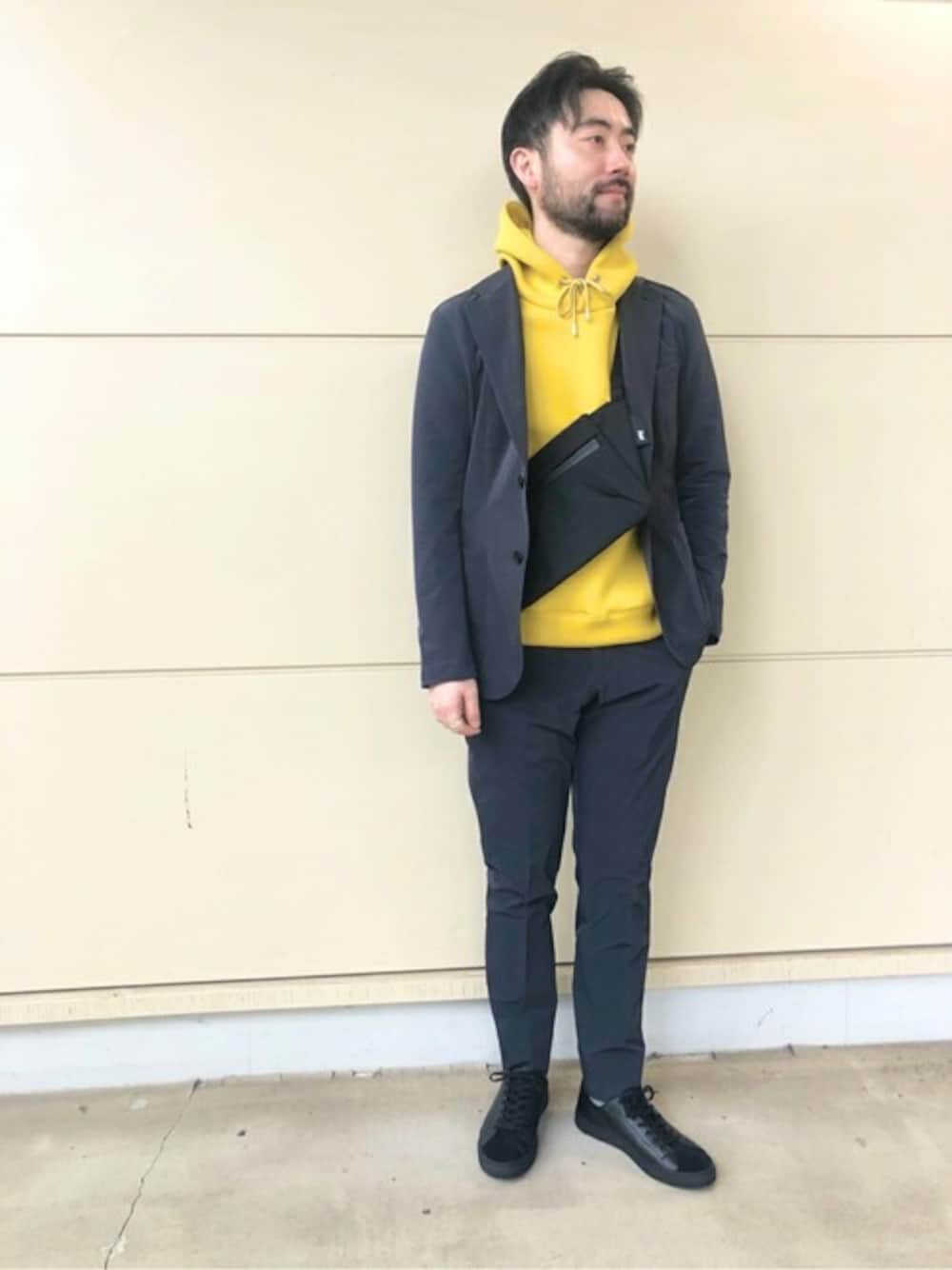 ブラック系のテーラードジャケット、ブラック系のその他パンツ、イエロー系のパーカーを着用したメンズの冬コーディネートの1枚目の写真
