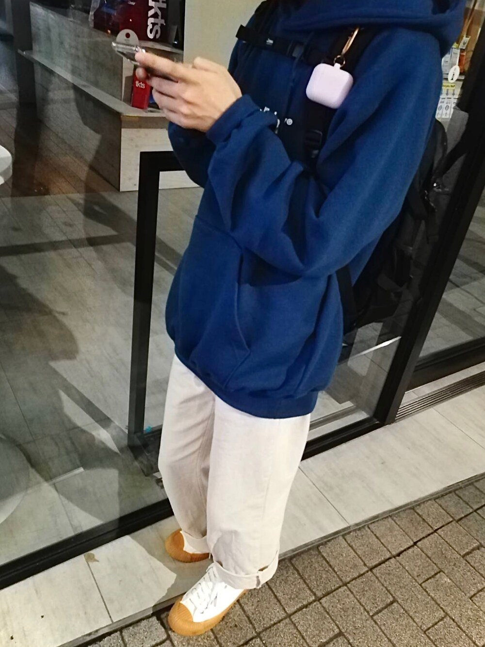 ブルー系のパーカー、ブラック系のバックパック/リュック、ホワイト系のスニーカーを着用したメンズの秋コーディネートの1枚目の写真