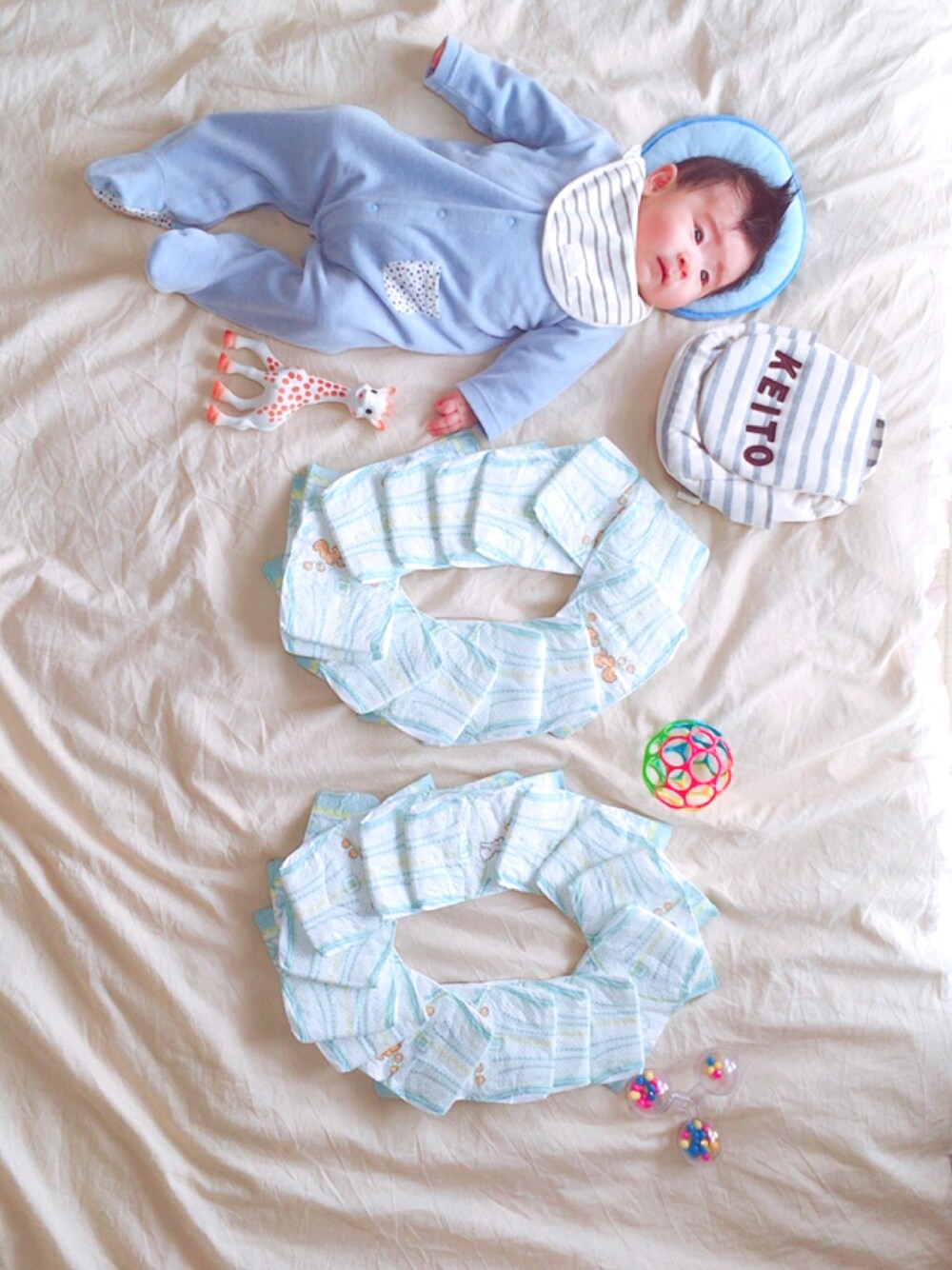 ブルー系のロンパース、ベージュ系のおもちゃを着用したキッズの冬コーディネートの1枚目の写真