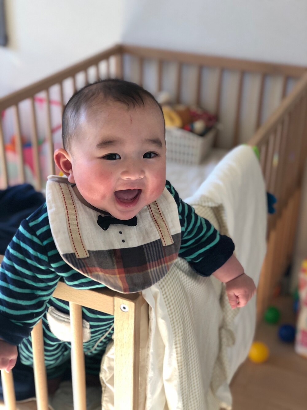 ベージュ系のスタイ/よだれかけ、グリーン系のロンパースを着用したキッズの冬コーディネートの1枚目の写真