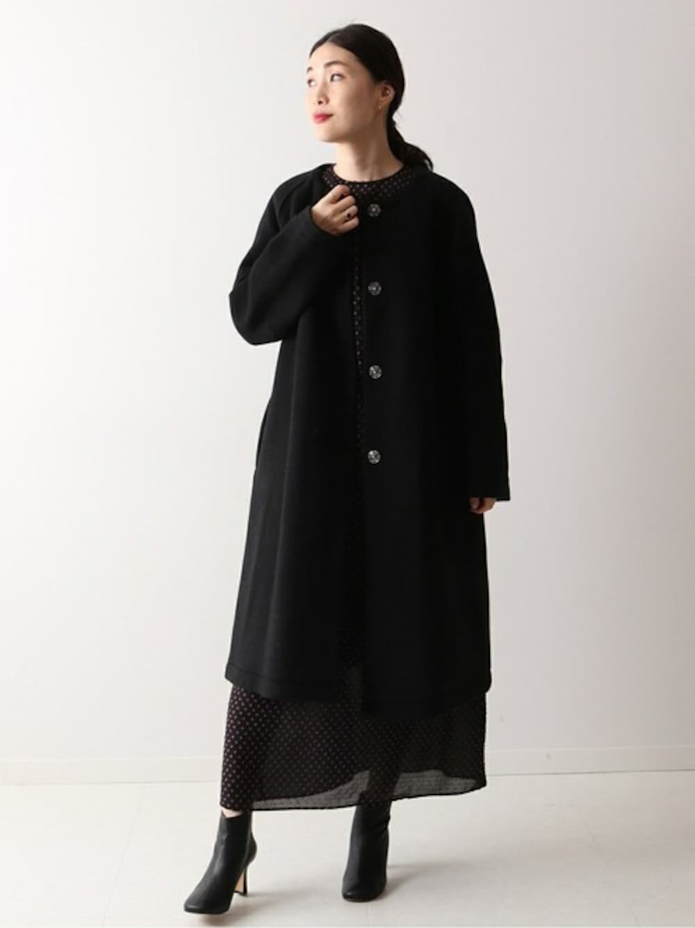 ブラック系のノーカラーコート、ブラック系のブーツを着用したレディースの冬コーディネートの1枚目の写真