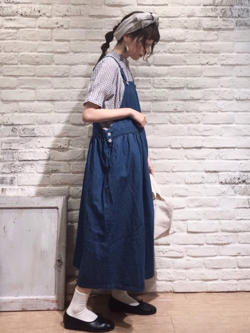 グレー系のシャツ/ブラウス、ブルー系のジャンパースカート、ベージュ系のエコバッグ/サブバッグを着用したレディースの春コーディネートの1枚目の写真