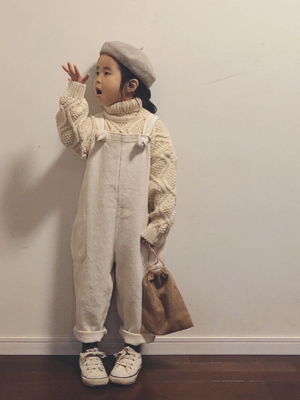 ベージュ系のニット/セーター、ホワイト系のオールインワン・サロペット、ホワイト系のスニーカーを着用したキッズの秋コーディネートの1枚目の写真