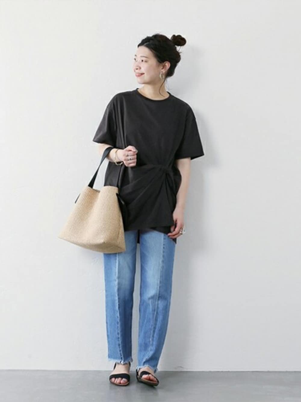 ブラック系のTシャツ/カットソー、ブルー系のデニムパンツ、ベージュ系のショルダーバッグを着用したレディースの春コーディネートの1枚目の写真
