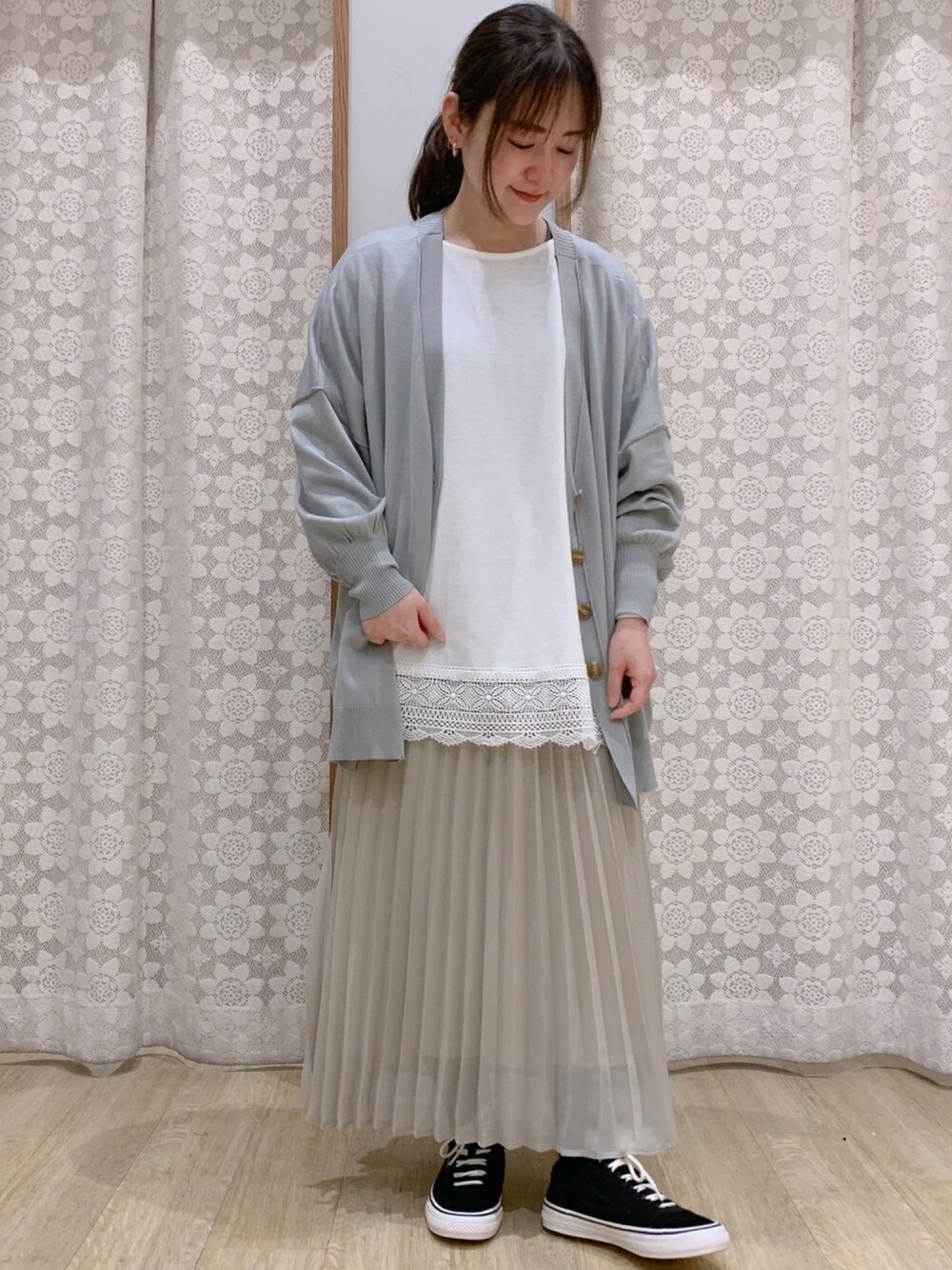 ホワイト系のTシャツ/カットソー、ベージュ系のスカート、ブラック系のスニーカーを着用したレディースの春コーディネートの1枚目の写真