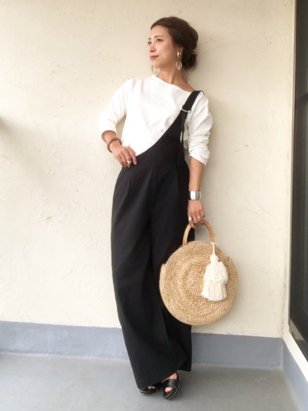 ホワイト系のTシャツ/カットソー、ブラック系のサロペット/オーバーオール、ベージュ系のかごバッグを着用したレディースの春コーディネートの1枚目の写真