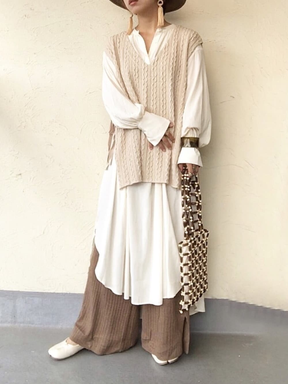 ホワイト系のベスト、ホワイト系のワンピース、ブラウン系のトートバッグを着用したレディースの夏コーディネートの1枚目の写真