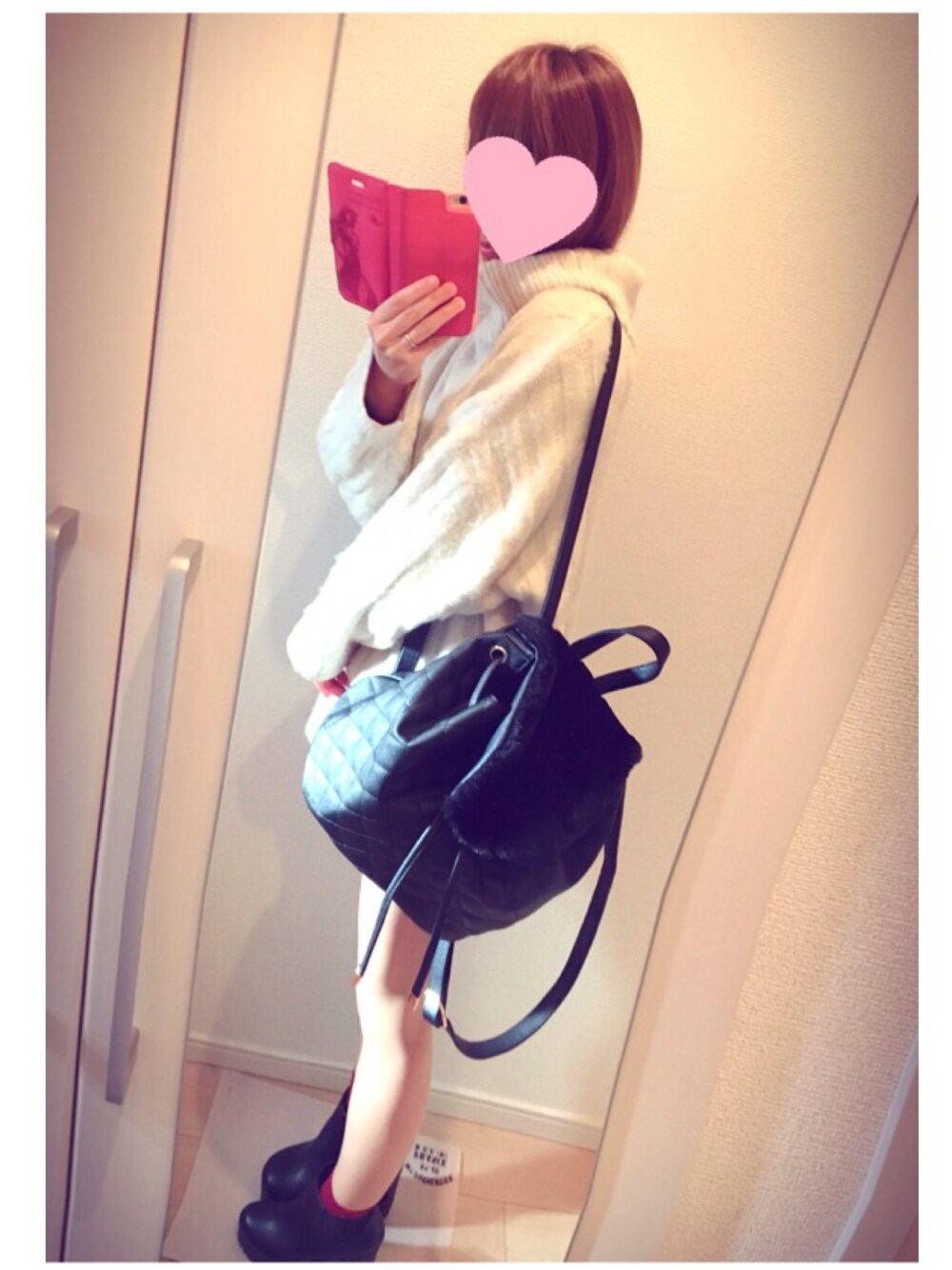 ブラック系のバックパック/リュック、ホワイト系のニット/セーター、ブラック系のブーツを着用したレディースの冬コーディネートの1枚目の写真