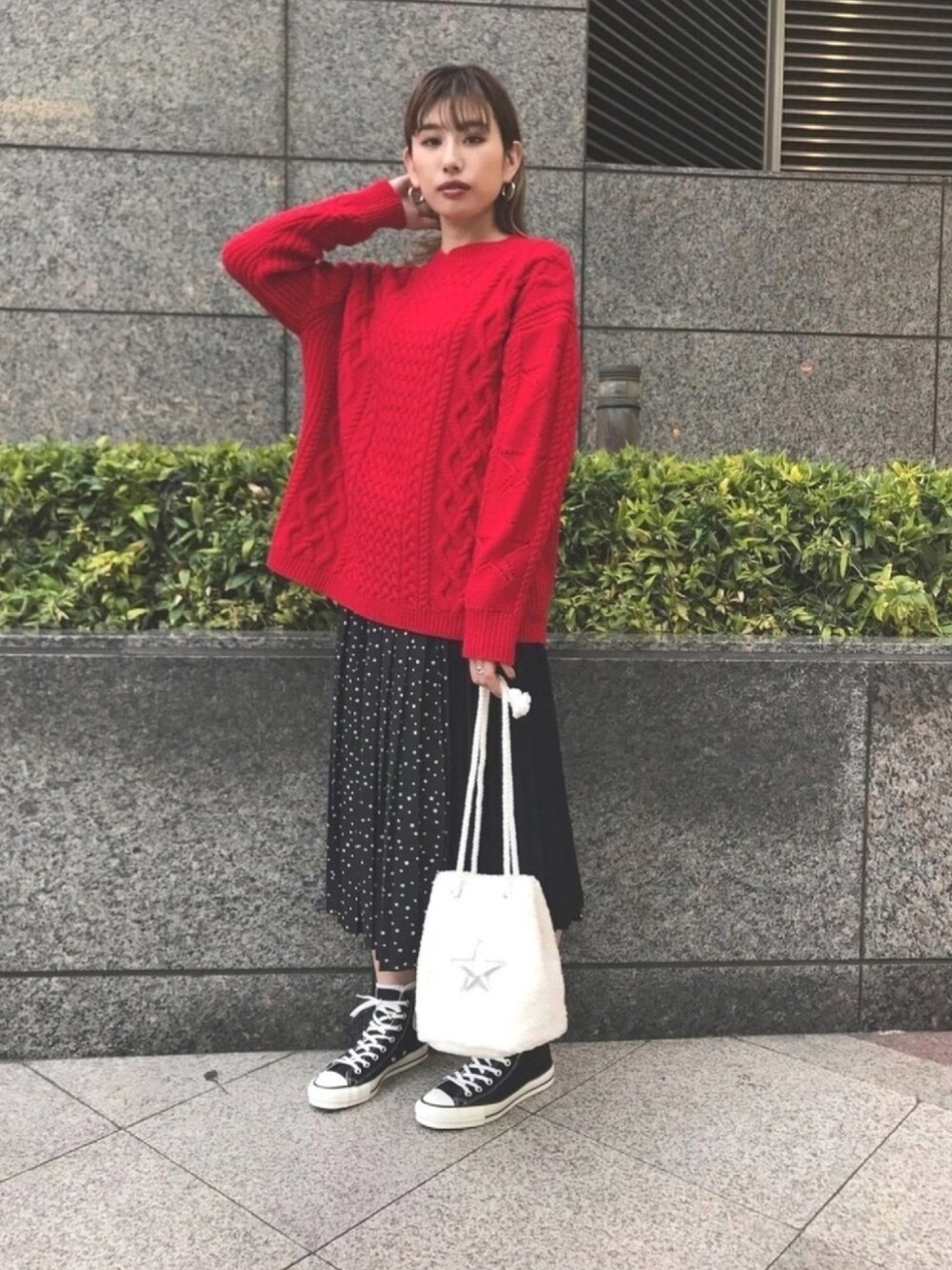 レッド系のニット/セーター、ブラック系のスカート、ホワイト系のハンドバッグを着用したレディースの冬コーディネートの1枚目の写真