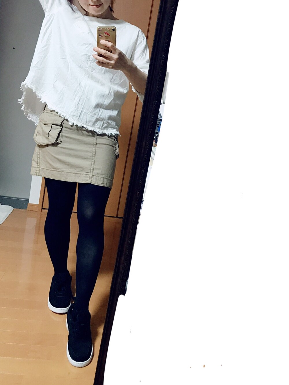 ブラック系のスニーカー、ブラウン系のデニムスカートを着用したレディースの秋コーディネートの1枚目の写真