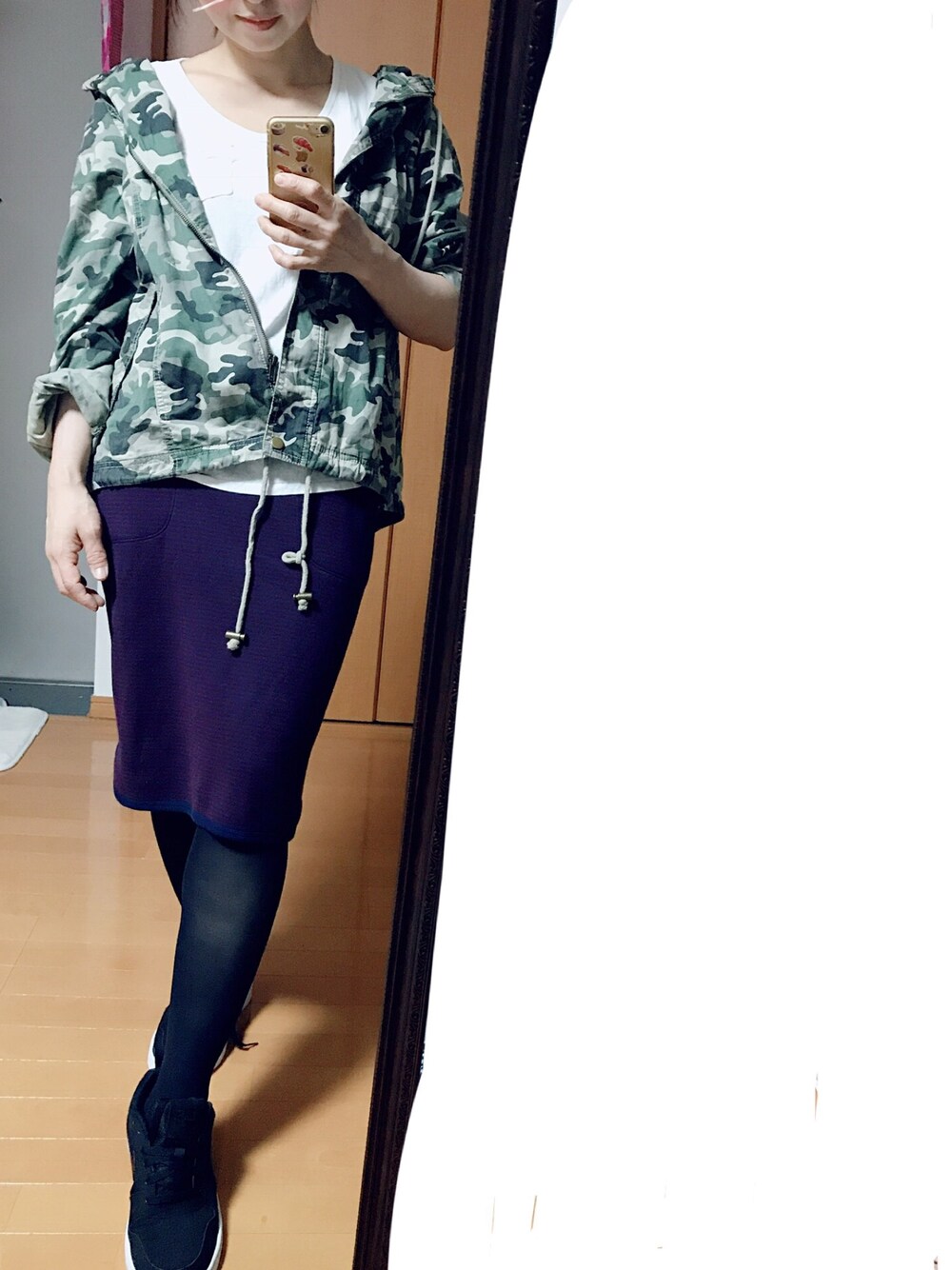 パープル系のスカート、ブラック系のスニーカーを着用したレディースの秋コーディネートの1枚目の写真