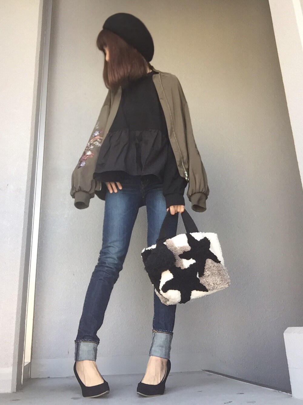 グリーン系のブルゾン、ブラック系のスウェット、ブルー系のデニムパンツを着用したレディースの冬コーディネートの1枚目の写真
