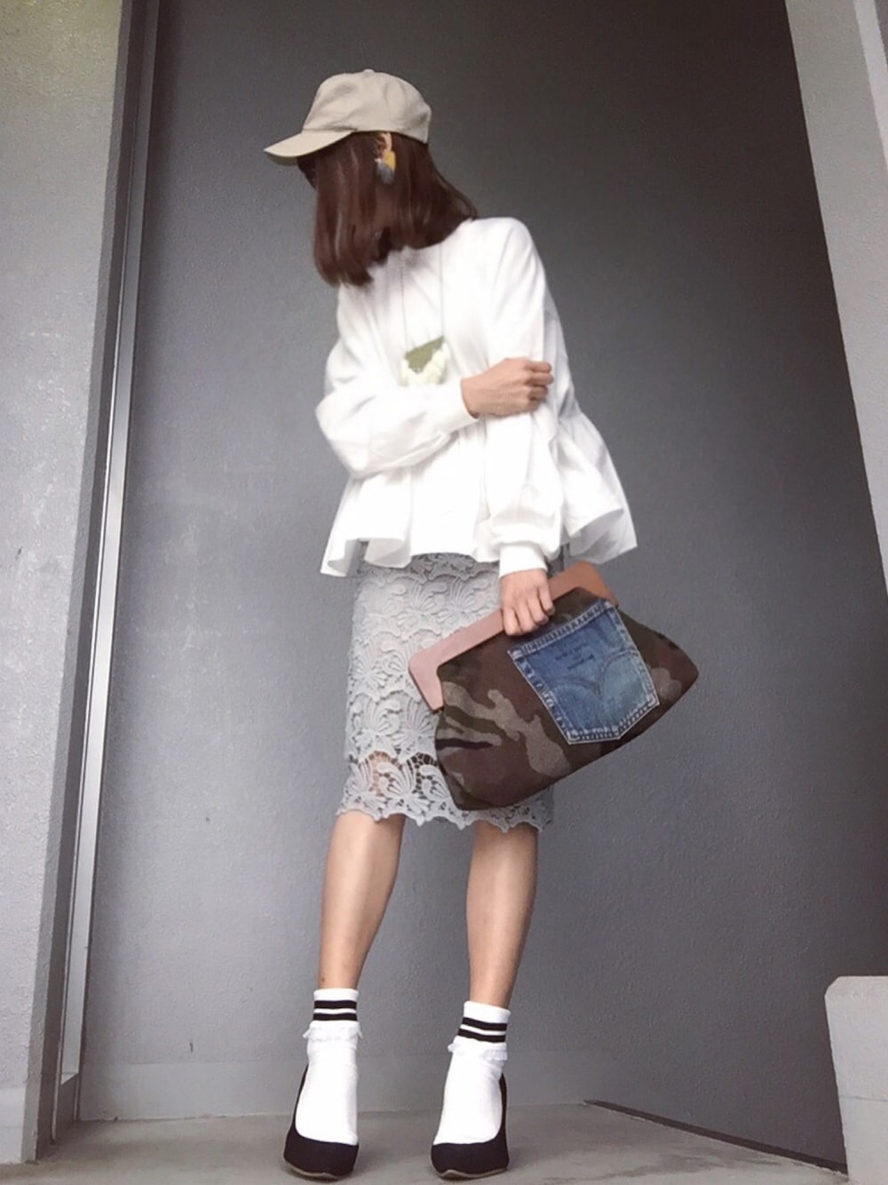 ホワイト系のスウェット、グレー系のスカート、ブラック系のパンプスを着用したレディースの春コーディネートの1枚目の写真