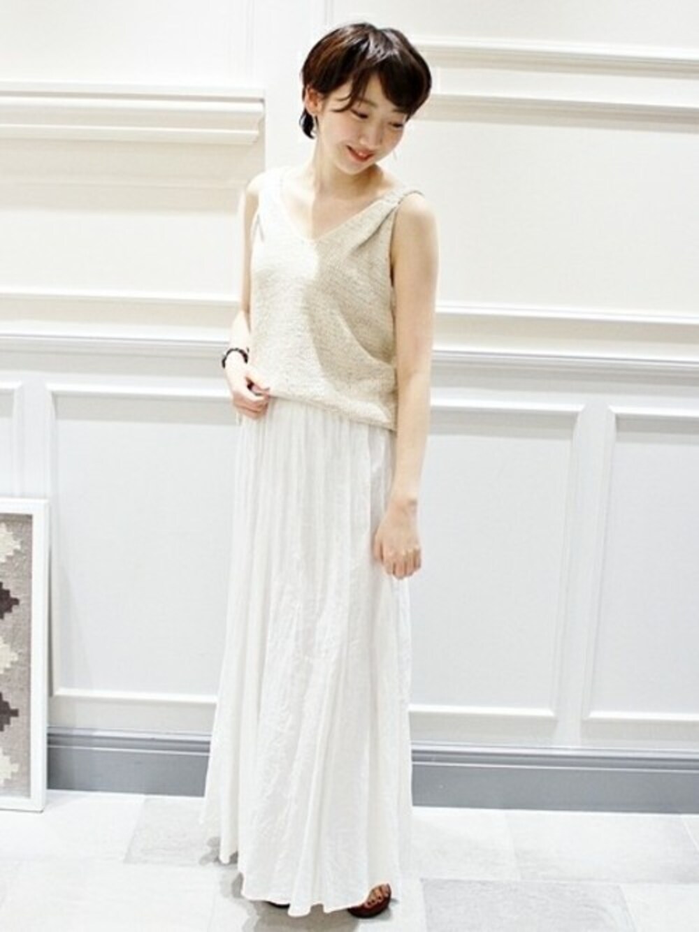 ホワイト系のスカート、ベージュ系のニット/セーター、ブラウン系のサンダルを着用したレディースの夏コーディネートの1枚目の写真