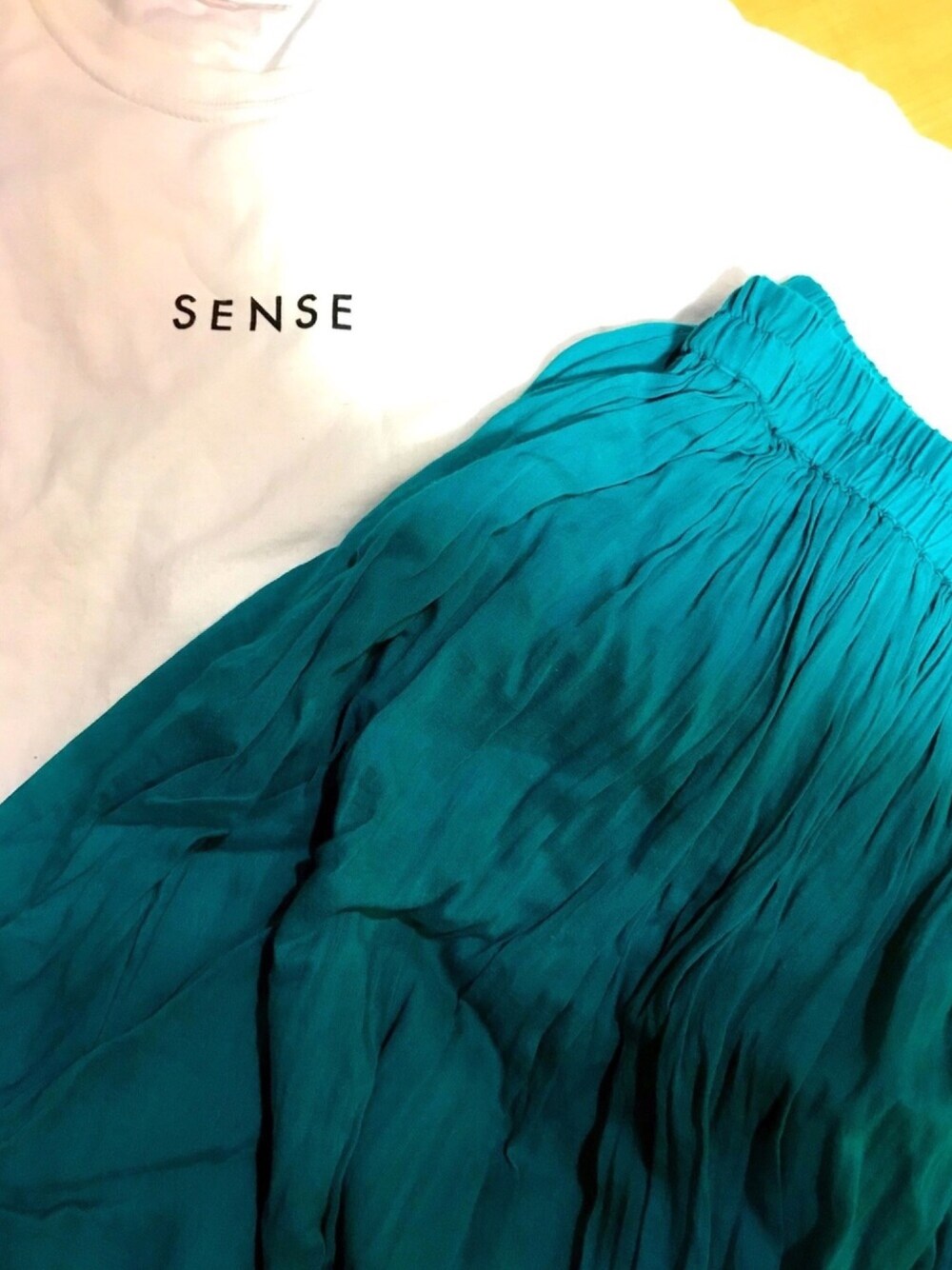 ホワイト系のTシャツ/カットソー、グリーン系のスカート、ブラック系のサンダルを着用したレディースの夏コーディネートの1枚目の写真