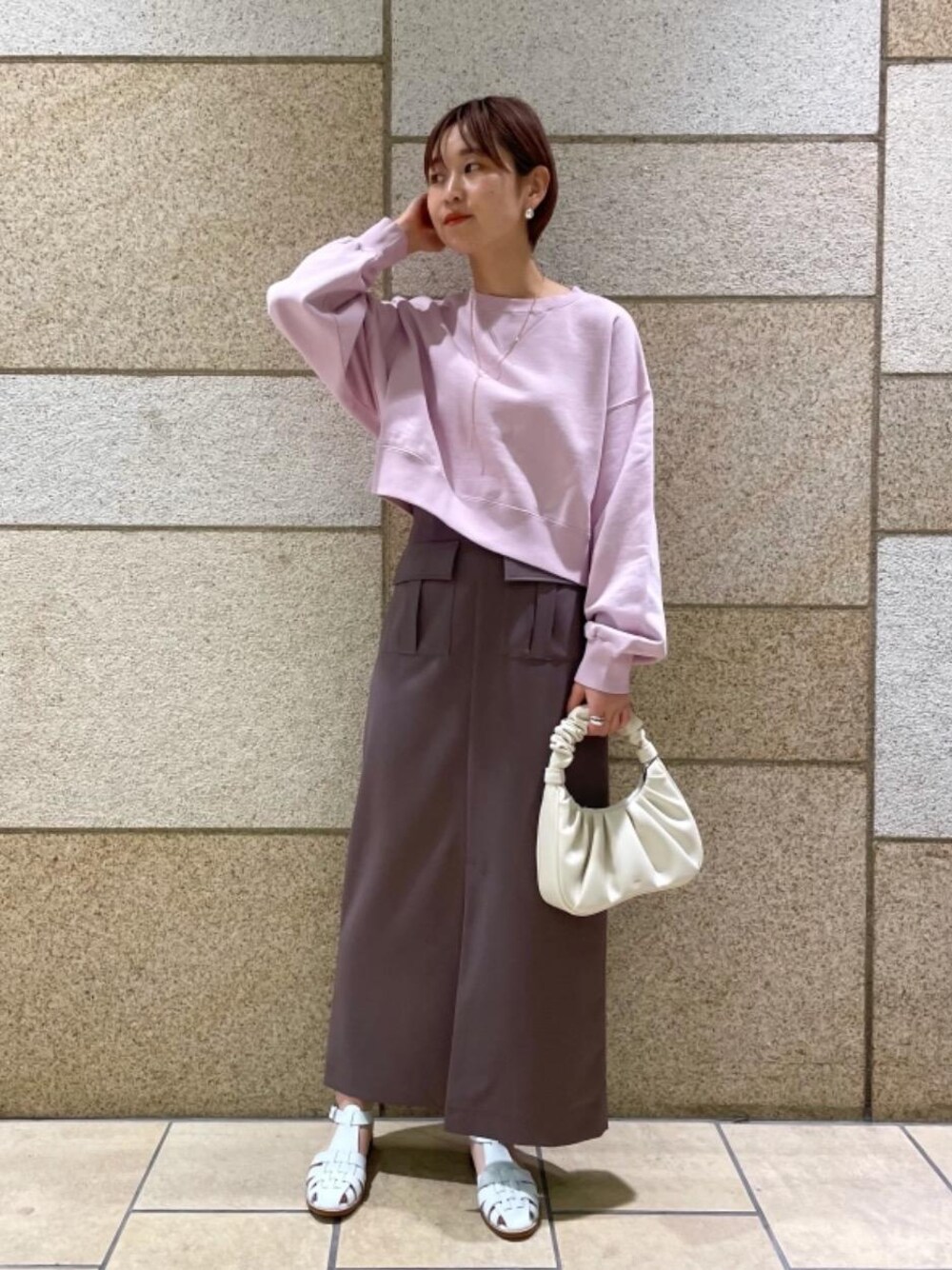 ピンク系のスウェット、ホワイト系のサンダル、ブラウン系のスカートを着用したレディースの冬コーディネートの1枚目の写真