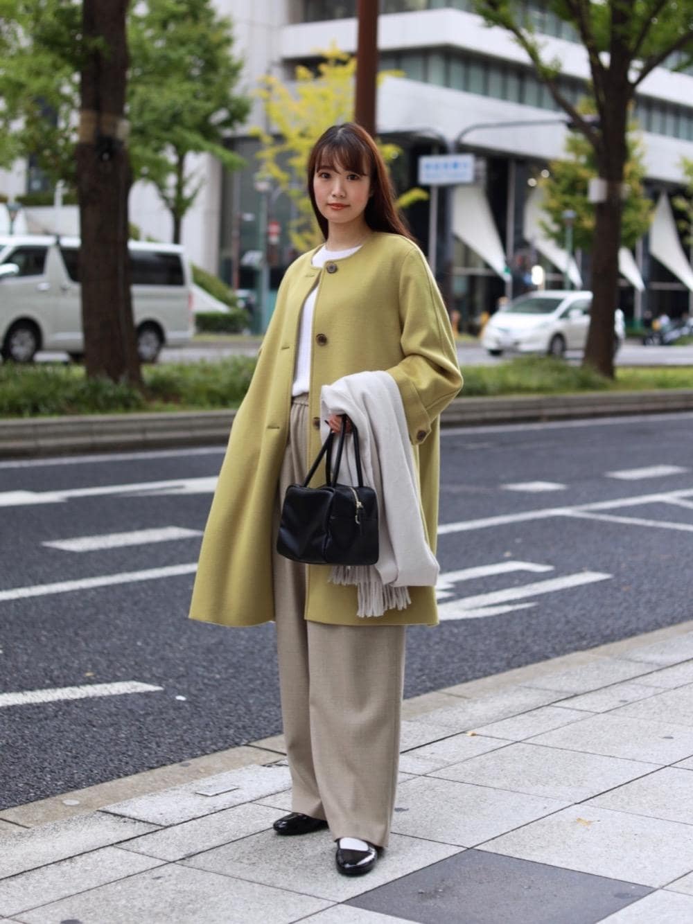 ブラック系のその他シューズ、ブラック系のボストンバッグ、イエロー系のその他アウターを着用したレディースの秋コーディネートの1枚目の写真