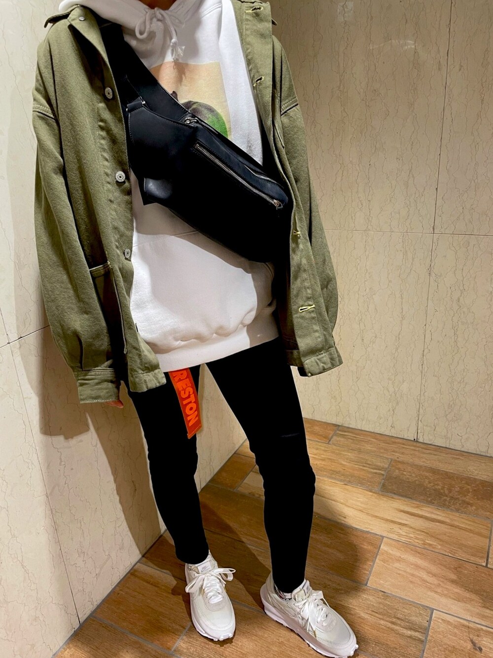 ブラック系のボディバッグ/ウエストポーチ、ホワイト系のパーカー、ブラック系のデニムパンツを着用したレディースの春コーディネートの1枚目の写真